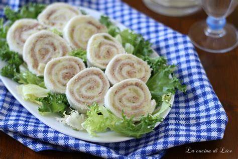 rotolini di tramezzini tagliati a rondelle e disposti su un piatto da portata, guarniti con rucola