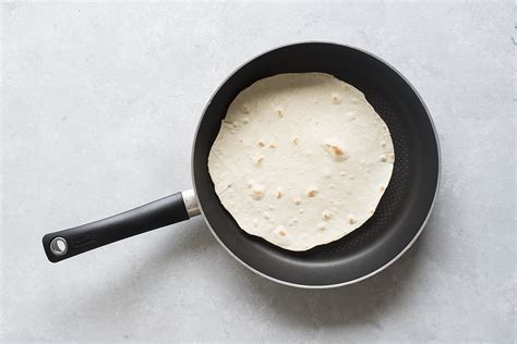 Primo piano di una piadina che viene scaldata in padella antiaderente