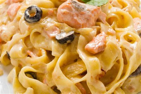 Piatto di pasta corta con crema di ceci e pezzetti di salmone affumicato, guarnito con erbe fresche