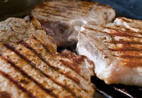 Una braciola di maiale succosa e dorata che cuoce su una piastra calda.