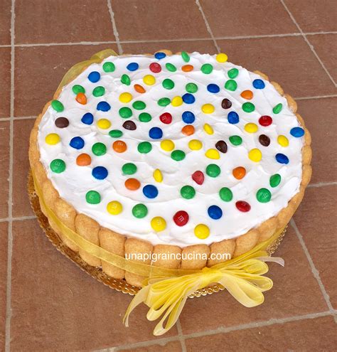 Illustrazione colorata di una cheesecake decorata con Smarties e ciuffi di panna.