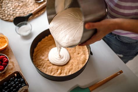 Primo piano della crema della cheesecake mentre viene mescolata, con pezzi di amaretti visibili.