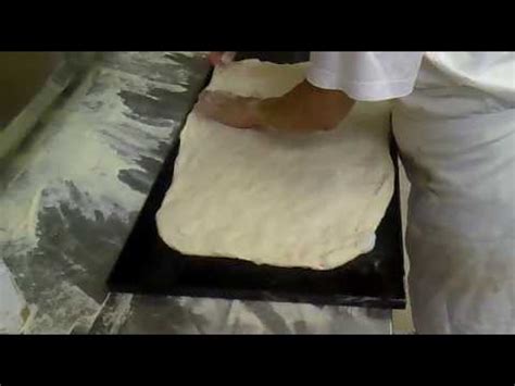 Stesura dell'impasto della pizza rettangolare su una teglia