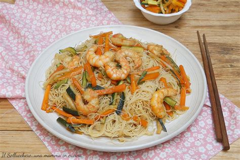 Composizione finale del piatto di spaghetti di riso con gamberi e verdure colorate, guarnito con prezzemolo e semi di sesamo.