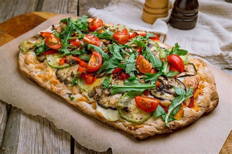 Primo piano di una Pinsa croccante e riccamente condita, con ingredienti freschi e colorati.