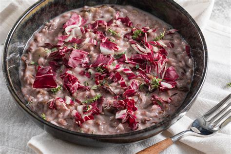 Primo piano di un risotto radicchio e pancetta cremoso, guarnito con prezzemolo fresco.