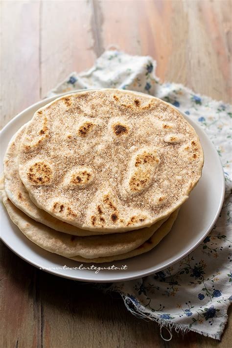 una piadina integrale che cuoce in padella, mostrando le bolle sulla superficie