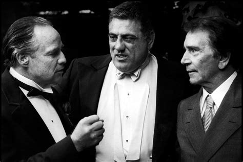 foto di Lenny Montana nei panni di Luca Brasi, con il suo caratteristico sorriso e l'abito elegante
