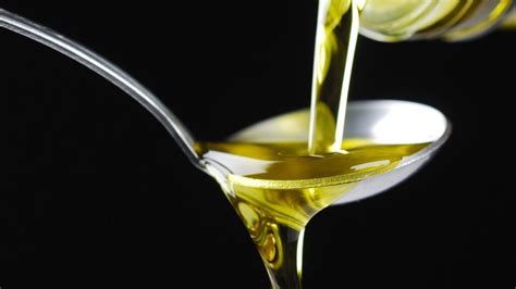 dettaglio di un filo d'olio extravergine d'oliva versato su un cucchiaio