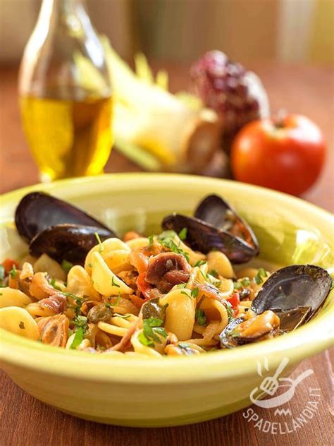 Immagine di orecchiette servite con cozze e carciofi, un piatto colorato e invitante.