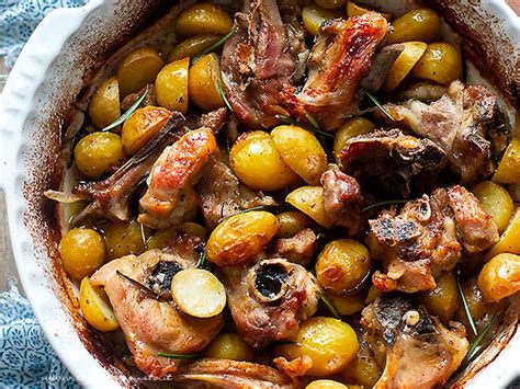 Piatto di capretto al forno servito con patate arrosto e rosmarino fresco.