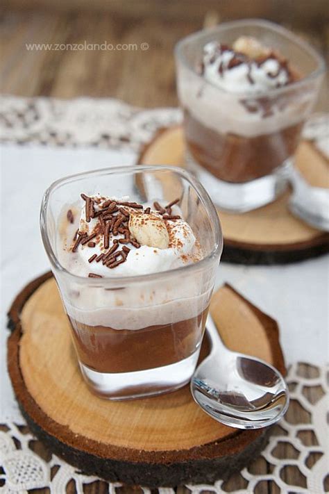 Immagine di bicchierini trasparenti con strati di crema di castagne e cioccolato, guarniti con panna montata e scaglie di cioccolato.