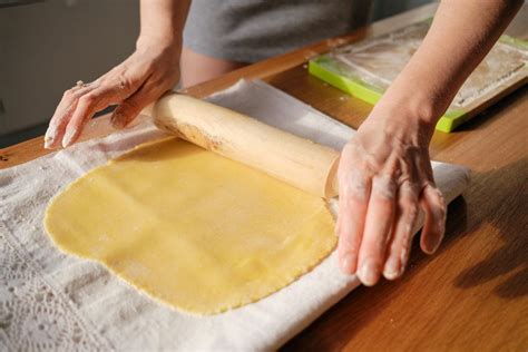 Mani che tirano delicatamente l'impasto dello strudel su un telo