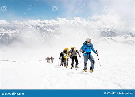 Gruppo di alpinisti con attrezzatura da spedizione davanti a un paesaggio montano imponente.