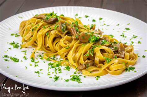Un piatto fumante di tagliatelle condite con funghi porcini secchi e prezzemolo tritato.