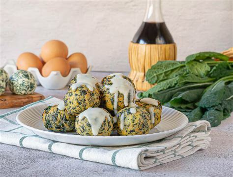Composizione di polpette di ricotta e cavolo nero impiattate con crema di pecorino