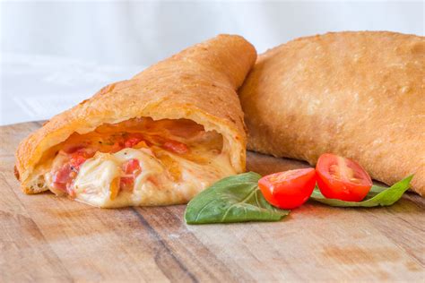 Immagine di pizze fritte a forma di panzerotto, farcite con friarielli, salame e mozzarella