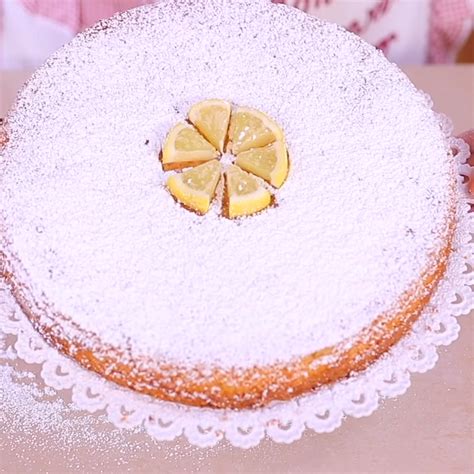 Immagine di una torta Caprese al cioccolato bianco e limone decorata con zucchero a velo