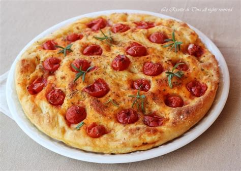 Focaccia con pomodorini freschi e rosmarino, pronta per essere infornata.
