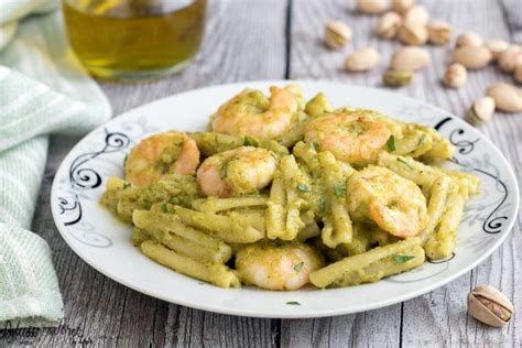 Immagine di un piatto di pasta con gamberi e pesto di pistacchi, ben presentato e invitante.