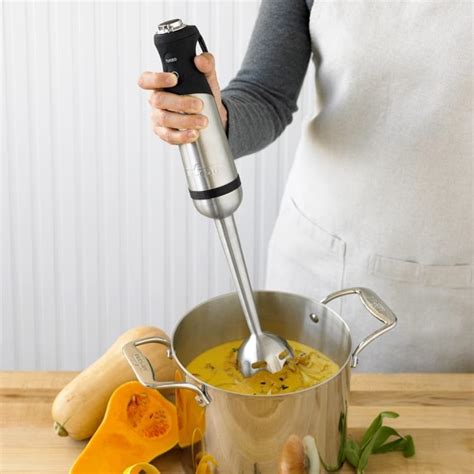 Immagine di una persona che utilizza un frullatore a immersione per rendere cremosa la zuppa di patate.