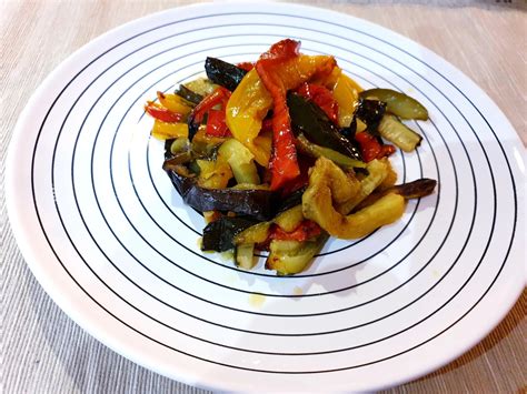 Composizione di verdure colorate (zucchine, peperoni, melanzane) disposte su una piastra calda.