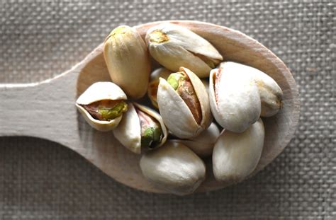 Immagine di pistacchi tostati e salati in una ciotola, con alcuni gusci sparsi intorno