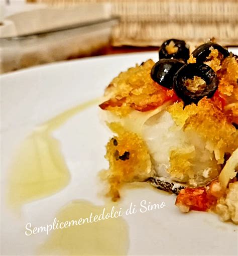 Immagine di un baccalà gratinato appena sfornato, con pomodorini dorati e erbe aromatiche
