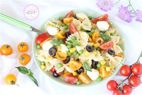 Una ciotola colorata di insalata di pasta fredda con pomodorini, olive, feta e basilico