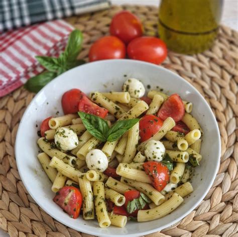 Primo piano di ingredienti freschi per l'insalata di pasta: pomodorini, olive, basilico, mozzarella