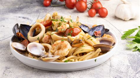 Immagine di un piatto fumante di spaghetti ai frutti di mare con pomodorini freschi e prezzemolo tritato