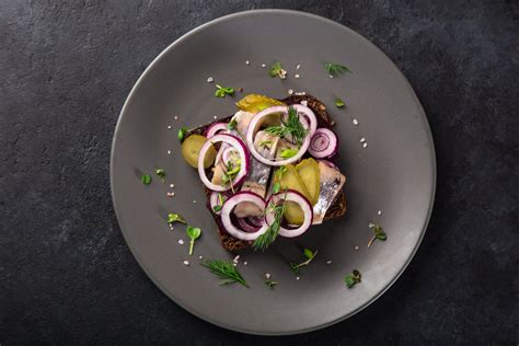 Un collage di ingredienti tipici per l'hamburger: cetriolini sottaceto, cipolle rosse affettate, foglie di lattuga, fette di pomodoro, ketchup e senape.