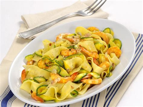 Immagine di un piatto di pasta con gamberi e zucchine, guarnito con prezzemolo fresco.