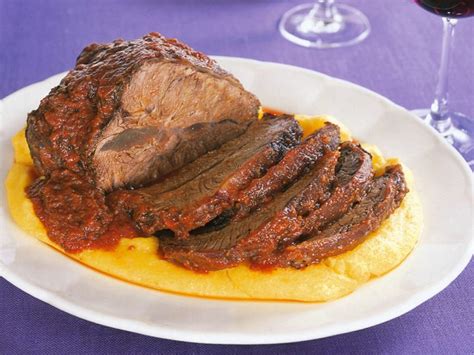 Un calice di vino Barolo accanto a un piatto di brasato al Barolo fumante.