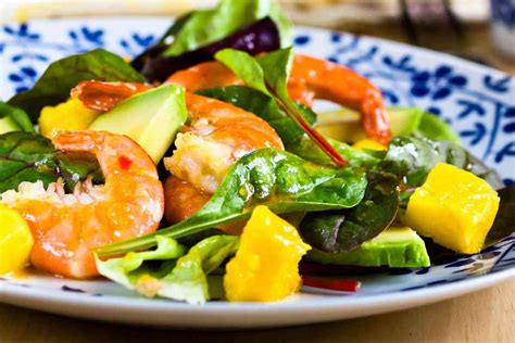 Immagine di un piatto unico colorato con gamberi, mango e verdure fresche.