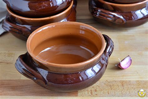 moscardini che cuociono lentamente in un coccio di terracotta con pomodorini e aglio
