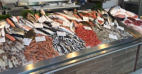 Banchi di pesce fresco in una pescheria con varietà di crostacei e molluschi