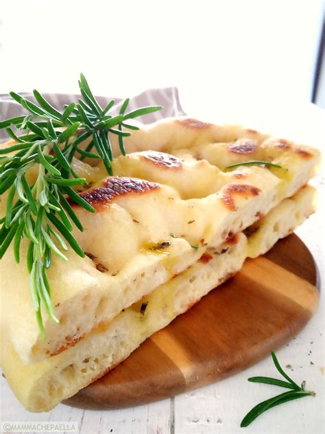 Immagine di una focaccia integrale soffice e dorata, tagliata a spicchi, con rosmarino sparso sulla superficie.