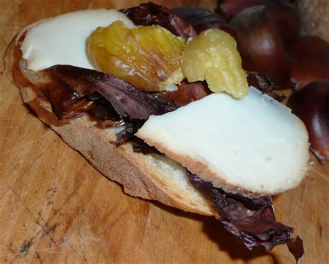 Primo piano di un crostino con pancetta, castagne e un filo di miele dorato.