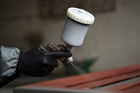 Primo piano di una mano che spruzza vernice da una bomboletta spray su una parte dell'auto