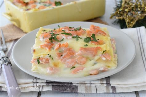 Primo piano di uno strato di lasagna al salmone e gorgonzola, con formaggio fuso e pezzi di salmone visibili.