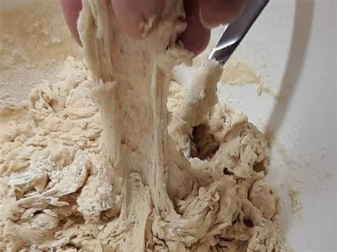 Immagine ravvicinata di un impasto perfettamente incordato e liscio nell'impastatrice.