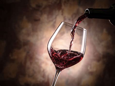 Immagine di un calice di vino rosso Delia Nivolelli DOP con frutti di bosco sullo sfondo