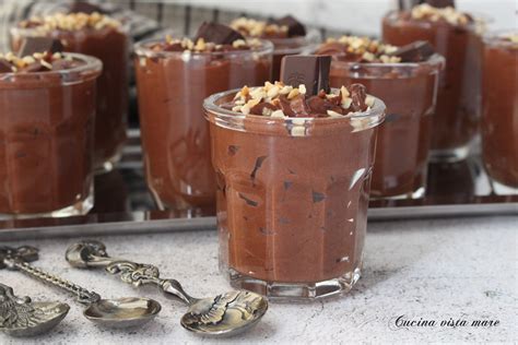 Immagine di mousse al cioccolato in coppette, con una spolverata di cacao o riccioli di cioccolato.