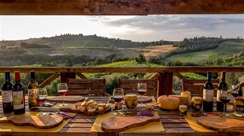 Un tavolo imbandito con tartufo, formaggi, vino e altri prodotti tipici toscani, con la città di Volterra sullo sfondo.