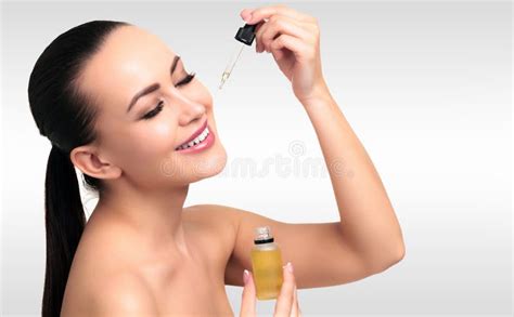 Primo piano di una donna che applica delicatamente olio sul viso