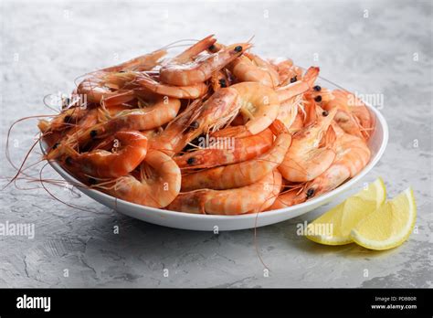 Gamberetti rossi cotti alla piastra su un piatto da portata con guarnizione di prezzemolo e spicchi di limone