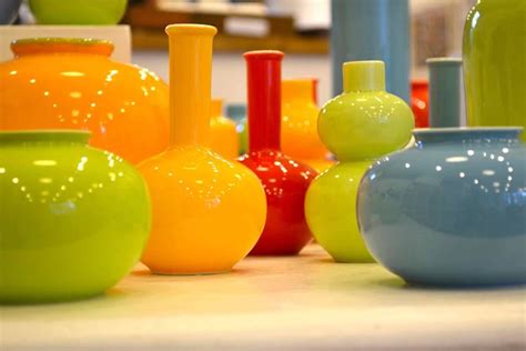 Composizione di vasi colorati e tazze utilizzate come vasetti, inseriti in una cesta di paglia