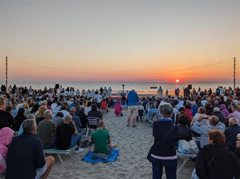 Alba sulla spiaggia di Rimini con persone che mangiano bomboloni