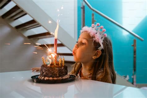 Bambina che soffia sulle candeline su una torta decorata a tema Frozen con Elsa e Olaf.